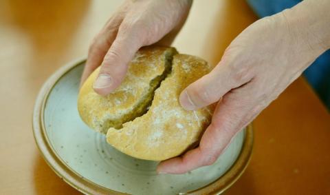 Zwei Hände halten einen Brotfladen und zerbrechen ihn