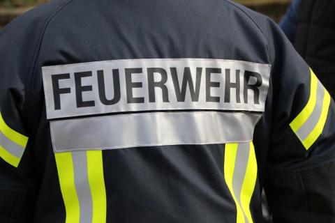 Foto einer Feuerwehruniform von hinten, man sieht groß den Aufdruck "Feuerwehr"