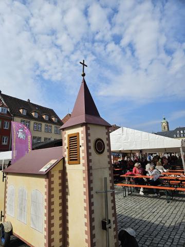 Die Wagenkirche auf dem Schweinfurter Fischmarkt. Blauer Himmel, im Hintergrund der Turm von St. Johannis