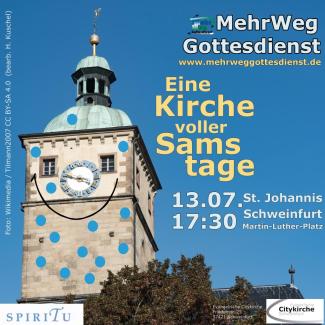 Der Turm der St. Johanniskirche Schweinfurt vor blauem Himmel. Die Kirchturmuhr sieht aus wie eine Nase zwischen den zwei Fenstern als Augen. Darunter ist mit einem Strich ein Mund angedeutet. Die Kirche ist übersät mit kleinen blauen Punkten.
